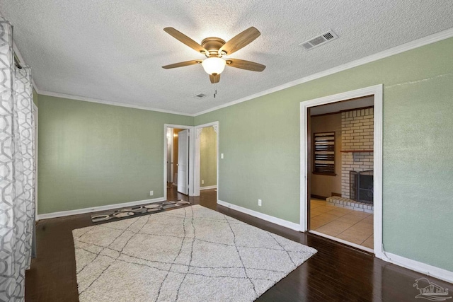 unfurnished bedroom featuring wood-type flooring, a brick fireplace, a textured ceiling, and crown molding