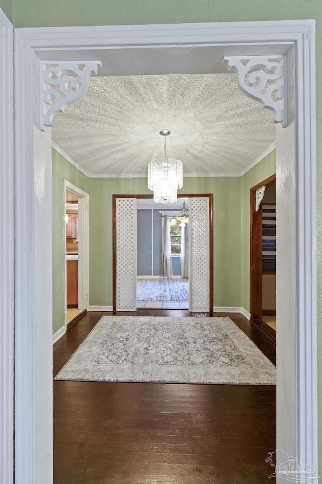 unfurnished dining area featuring an inviting chandelier, crown molding, dark hardwood / wood-style floors, and a textured ceiling