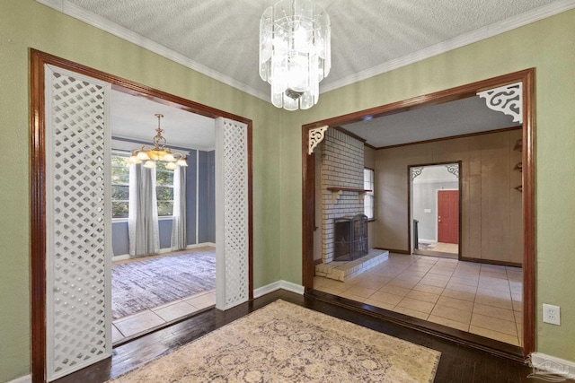 interior space featuring a chandelier, a brick fireplace, a textured ceiling, ornamental molding, and dark hardwood / wood-style floors