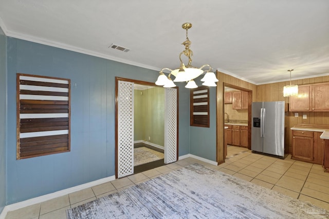 unfurnished dining area with crown molding, a chandelier, sink, and light tile patterned floors