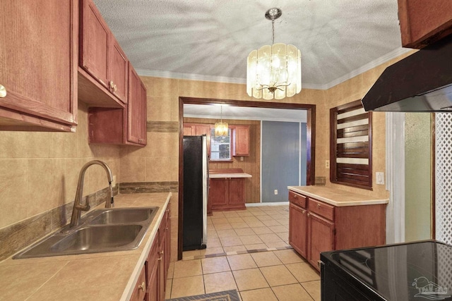 kitchen with sink, crown molding, ventilation hood, hanging light fixtures, and stainless steel fridge