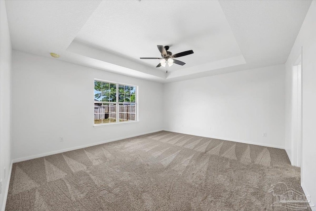 6914 Raburn Rd, Pensacola, FL 32526 - spare room featuring carpet floors, a tray ceiling, baseboards, and ceiling fan
