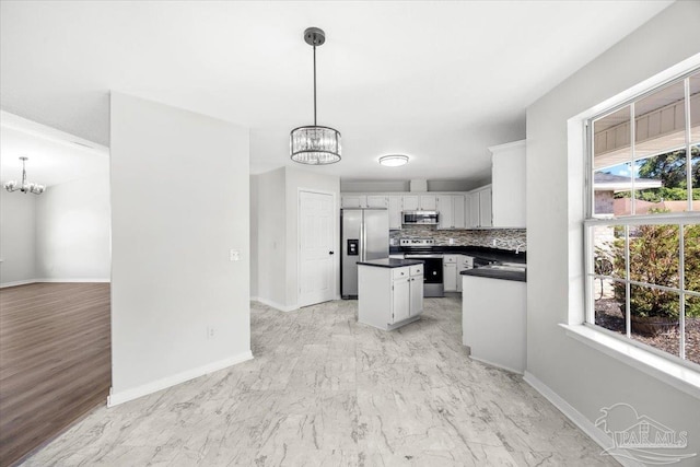6914 Raburn Rd, Pensacola, FL 32526 - kitchen featuring decorative backsplash, dark countertops, baseboards, appliances with stainless steel finishes, and a notable chandelier