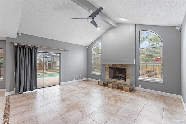 unfurnished living room featuring a stone fireplace, lofted ceiling with beams, a healthy amount of sunlight, and a textured ceiling