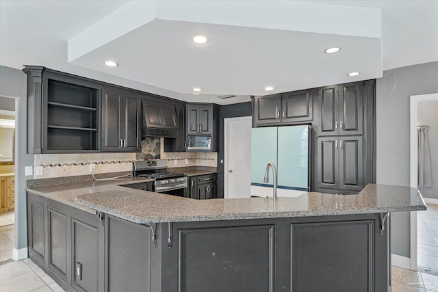 kitchen featuring kitchen peninsula, appliances with stainless steel finishes, tasteful backsplash, light stone counters, and light tile patterned floors