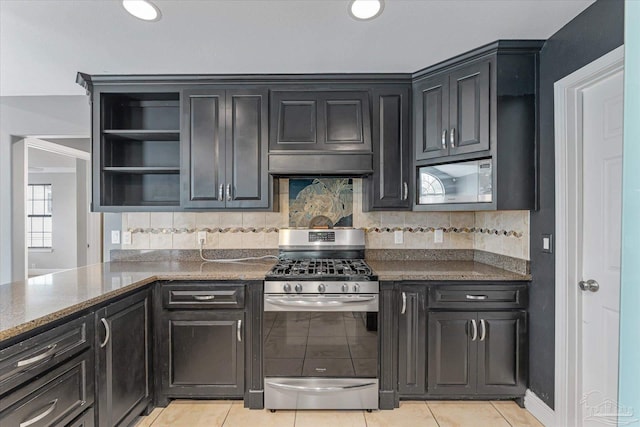 kitchen featuring backsplash, dark stone counters, ventilation hood, light tile patterned floors, and appliances with stainless steel finishes