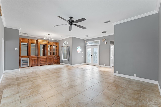 unfurnished living room with french doors, ceiling fan with notable chandelier, wine cooler, light tile patterned floors, and ornamental molding