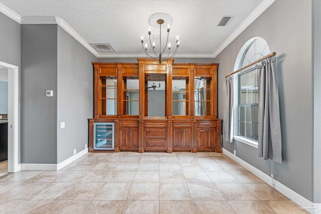 unfurnished dining area with ornamental molding, a textured ceiling, a notable chandelier, wine cooler, and light tile patterned flooring