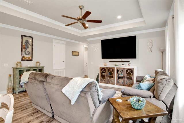 living room featuring a raised ceiling, ceiling fan, and light hardwood / wood-style floors