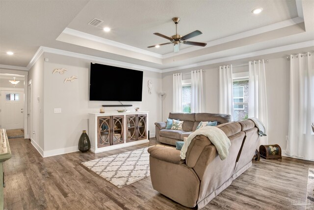 living room with a raised ceiling, light hardwood / wood-style flooring, and ceiling fan