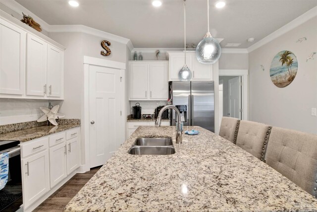 kitchen with hanging light fixtures, stainless steel appliances, a kitchen island with sink, and sink