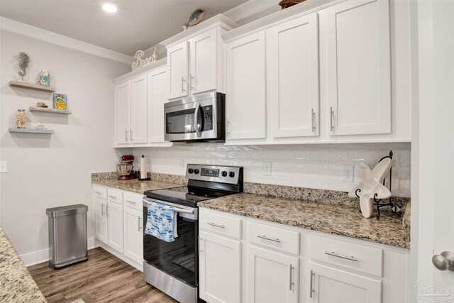 kitchen with crown molding, white cabinetry, light hardwood / wood-style flooring, stainless steel appliances, and decorative backsplash