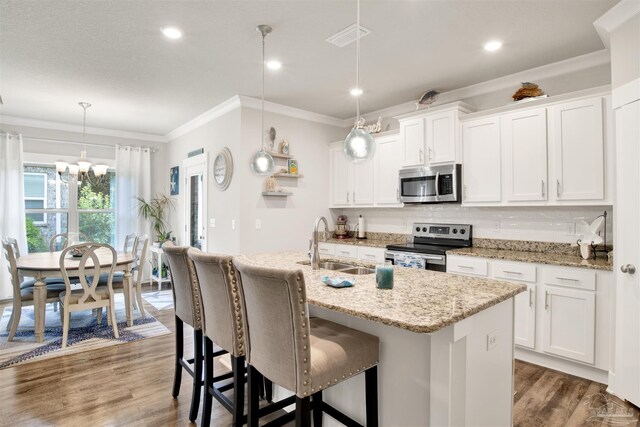 kitchen featuring appliances with stainless steel finishes, white cabinetry, hardwood / wood-style flooring, and a notable chandelier