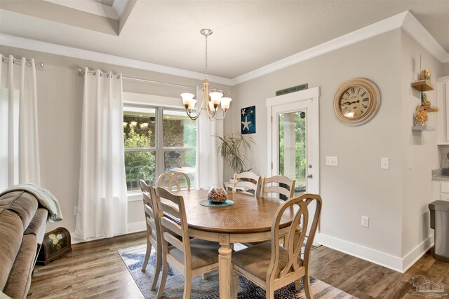 dining area featuring ornamental molding, a wealth of natural light, hardwood / wood-style floors, and a notable chandelier