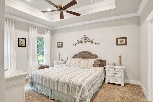 carpeted bedroom with a tray ceiling and ceiling fan