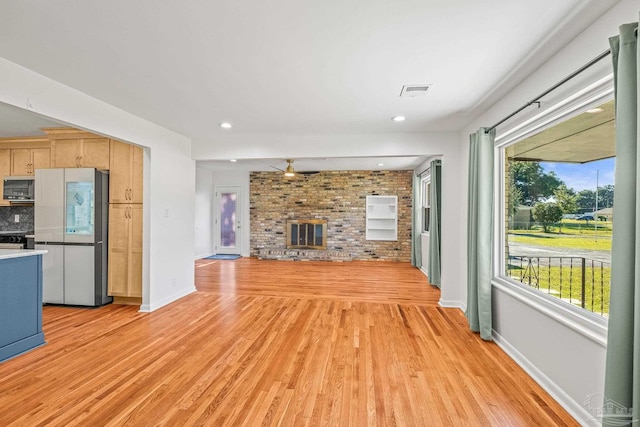 7332 Maxam Ave, Pensacola, FL 32503 - unfurnished living room featuring a brick fireplace, light hardwood / wood-style flooring, ceiling fan, and brick wall
