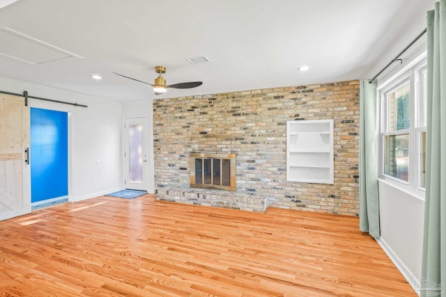 7332 Maxam Ave, Pensacola, FL 32503 - unfurnished living room with a brick fireplace, light hardwood / wood-style flooring, ceiling fan, and brick wall
