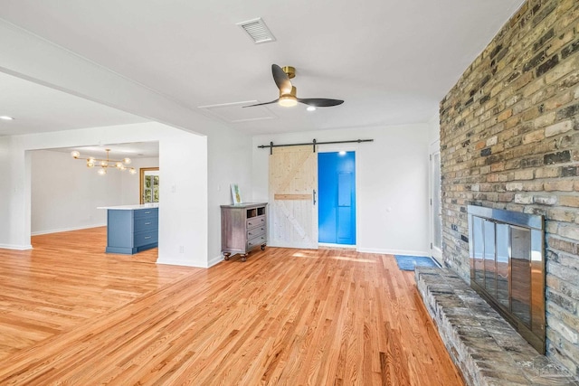 7332 Maxam Ave, Pensacola, FL 32503 - unfurnished living room with a barn door, light hardwood / wood-style flooring, a fireplace, and ceiling fan with notable chandelier