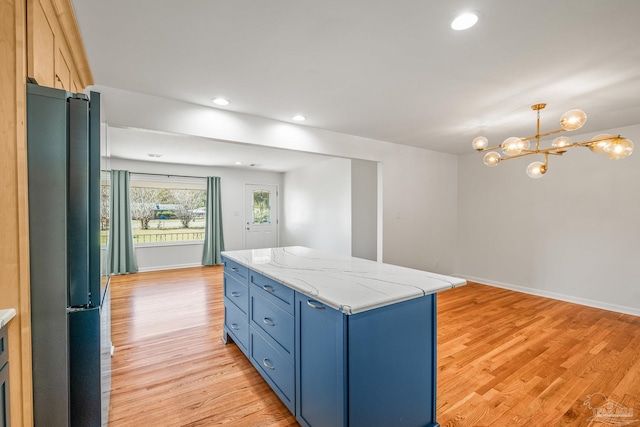 7332 Maxam Ave, Pensacola, FL 32503 - kitchen featuring blue cabinets, a notable chandelier, light hardwood / wood-style floors, a kitchen island, and fridge