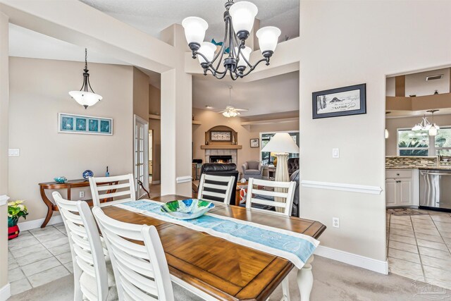 dining area featuring a tile fireplace, a towering ceiling, ceiling fan, and light tile patterned flooring