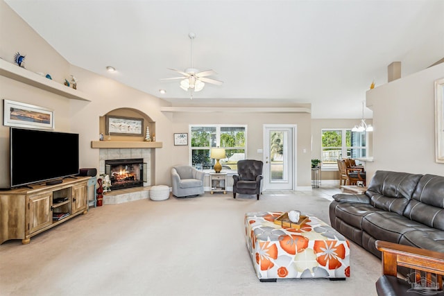 living room featuring ceiling fan with notable chandelier, carpet floors, and a tiled fireplace