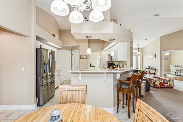 kitchen featuring tasteful backsplash, kitchen peninsula, a breakfast bar, white cabinets, and appliances with stainless steel finishes