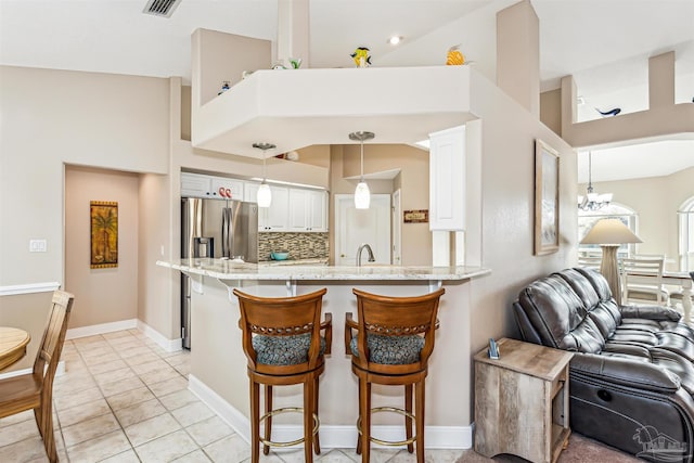 kitchen featuring white cabinetry, hanging light fixtures, tasteful backsplash, kitchen peninsula, and a kitchen bar