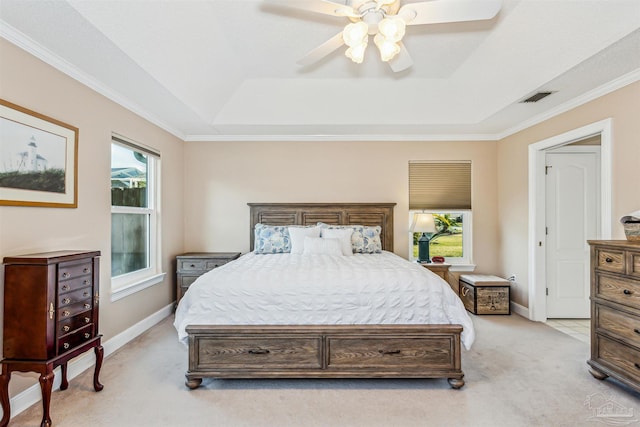 bedroom with ceiling fan, multiple windows, light carpet, and a tray ceiling