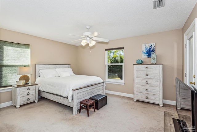 carpeted bedroom with ceiling fan and a textured ceiling