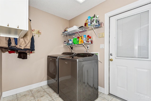 clothes washing area with cabinets, light tile patterned floors, a textured ceiling, and washer and dryer