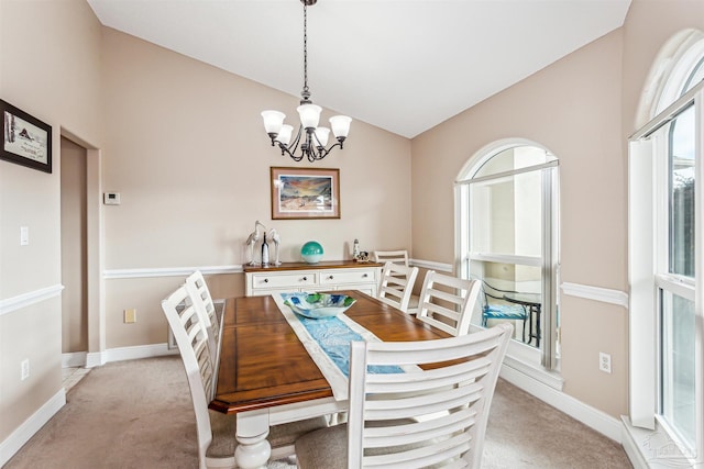 carpeted dining space featuring a chandelier and lofted ceiling