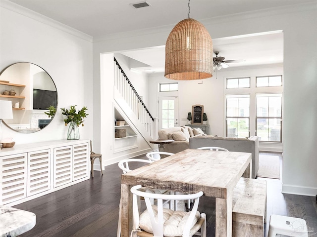 dining room with built in shelves, ornamental molding, and dark hardwood / wood-style floors