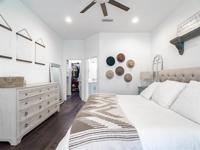 bedroom with dark wood-type flooring, ceiling fan, ensuite bathroom, a walk in closet, and a closet