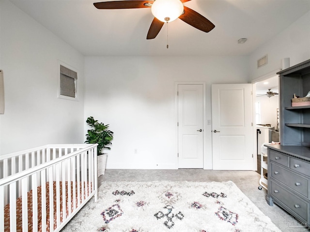 unfurnished bedroom featuring a nursery area, light carpet, ceiling fan, and a closet