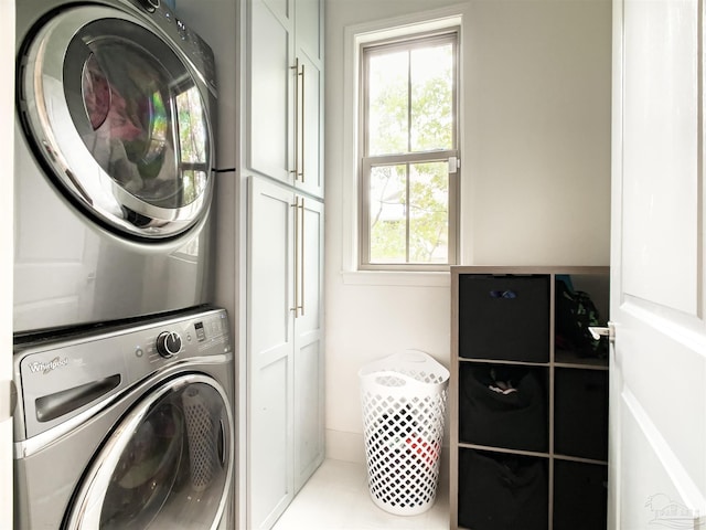 laundry area with cabinets, stacked washer / dryer, and tile patterned floors