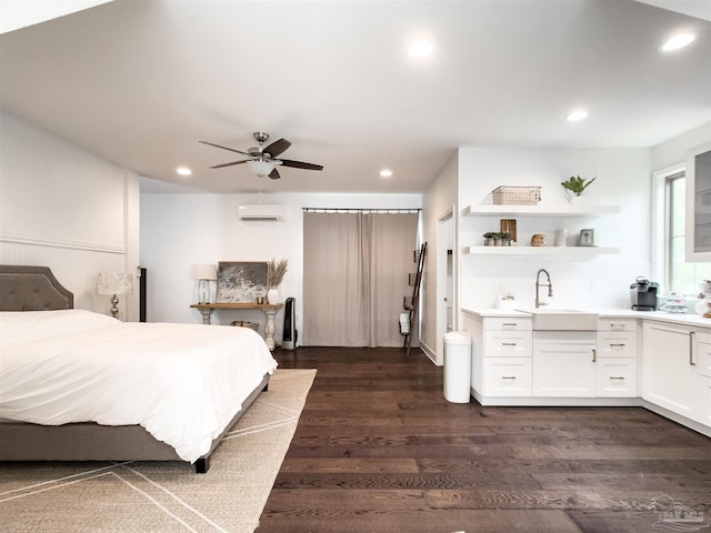 bedroom with dark hardwood / wood-style floors, an AC wall unit, sink, and ceiling fan