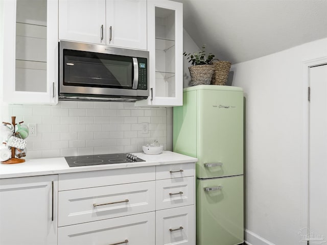 kitchen featuring tasteful backsplash, black electric stovetop, refrigerator, and white cabinets