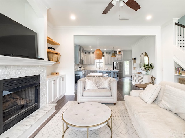 living room featuring ceiling fan, ornamental molding, dark hardwood / wood-style flooring, and sink