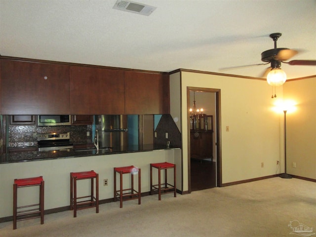 kitchen with appliances with stainless steel finishes, decorative backsplash, sink, ceiling fan, and dark brown cabinets