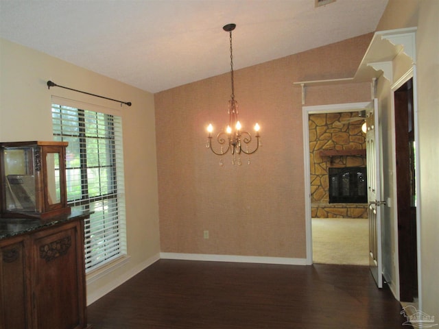 dining space with dark hardwood / wood-style floors, lofted ceiling, a notable chandelier, and a fireplace