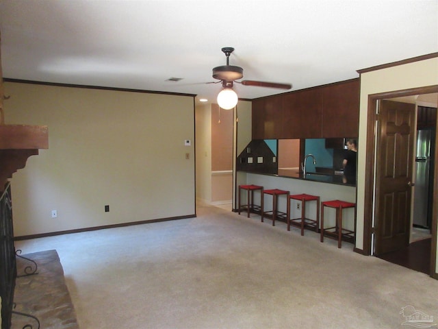 carpeted living room featuring ceiling fan, sink, and ornamental molding