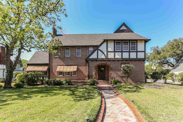 2020 E Mallory St, Pensacola, FL 32503 - english style home featuring a shingled roof, brick siding, a chimney, and a front lawn