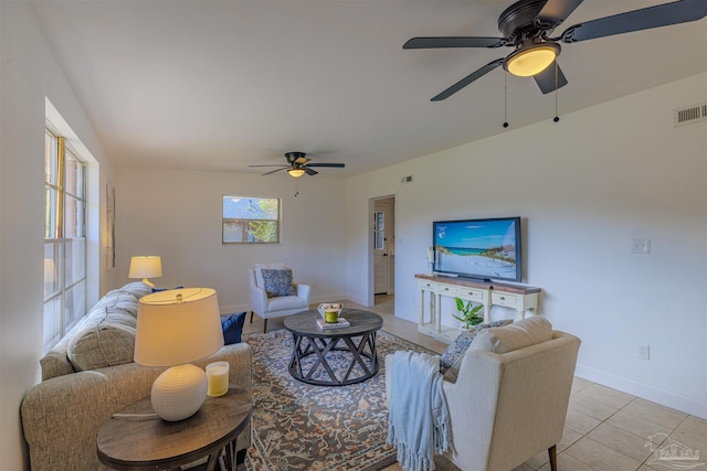 living room with light tile patterned floors, visible vents, baseboards, and ceiling fan