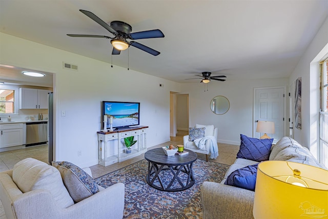 living area featuring light tile patterned flooring, visible vents, baseboards, and ceiling fan