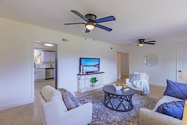 living room with light tile patterned floors, visible vents, baseboards, and a ceiling fan