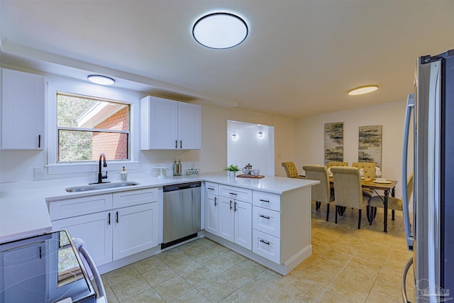 kitchen with a sink, appliances with stainless steel finishes, a peninsula, and white cabinetry