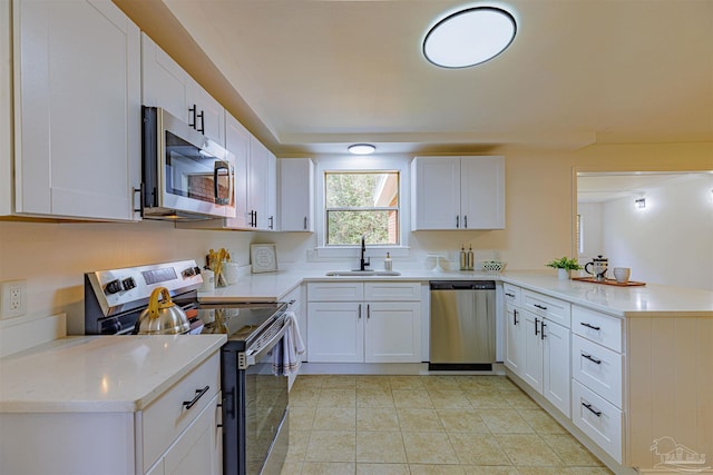 kitchen with appliances with stainless steel finishes, white cabinetry, a peninsula, and a sink