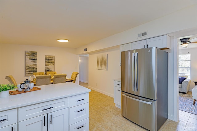 kitchen featuring baseboards, visible vents, freestanding refrigerator, light countertops, and white cabinets