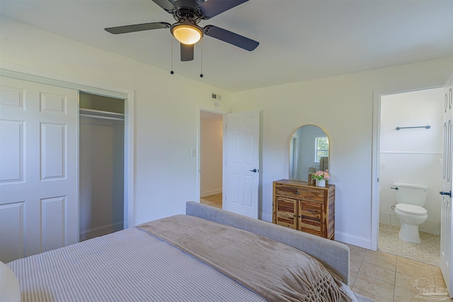 bedroom featuring connected bathroom, ceiling fan, arched walkways, light tile patterned flooring, and a closet