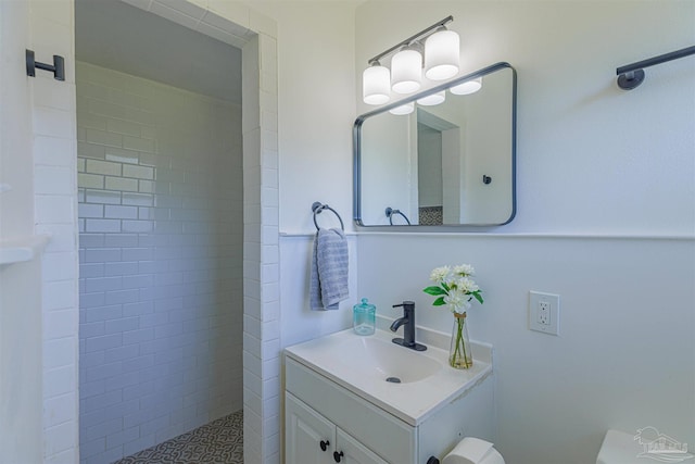 full bath featuring a tile shower and vanity